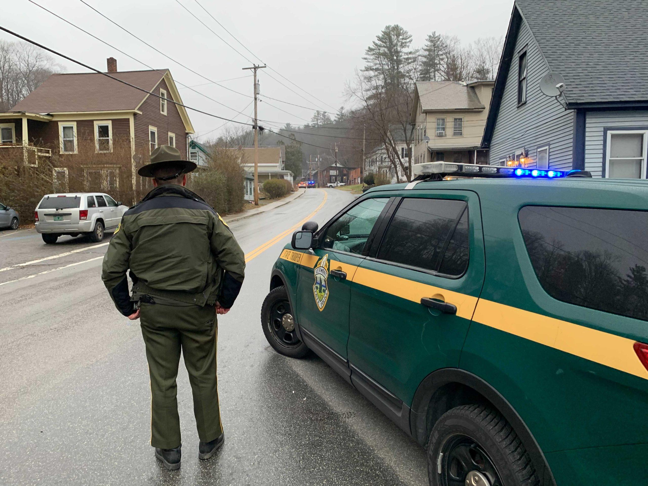 Vermont state trooper standing beside a patrol car