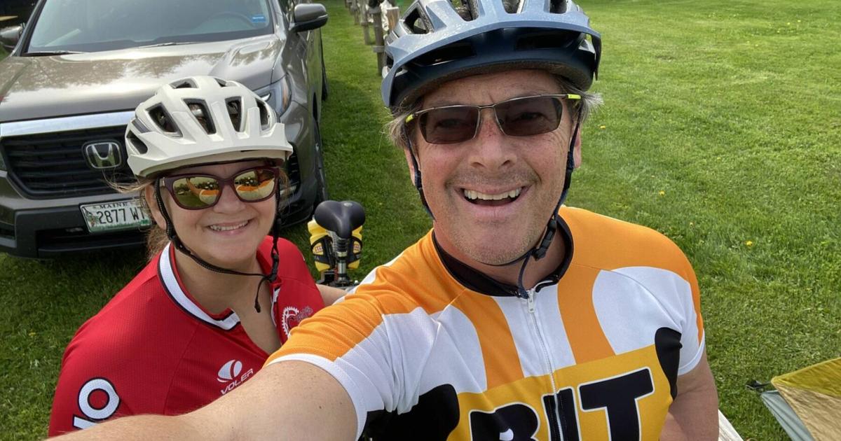 Two cyclists wearing helmets posing for a photo