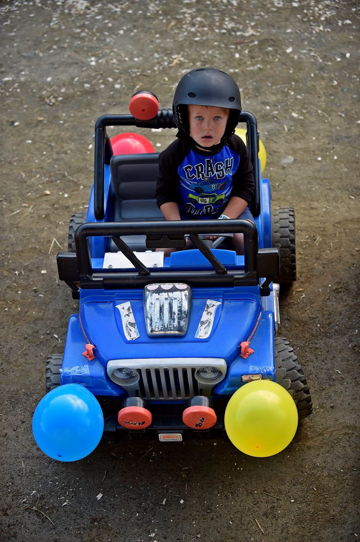 A child seated in a decorated miniature vehicle