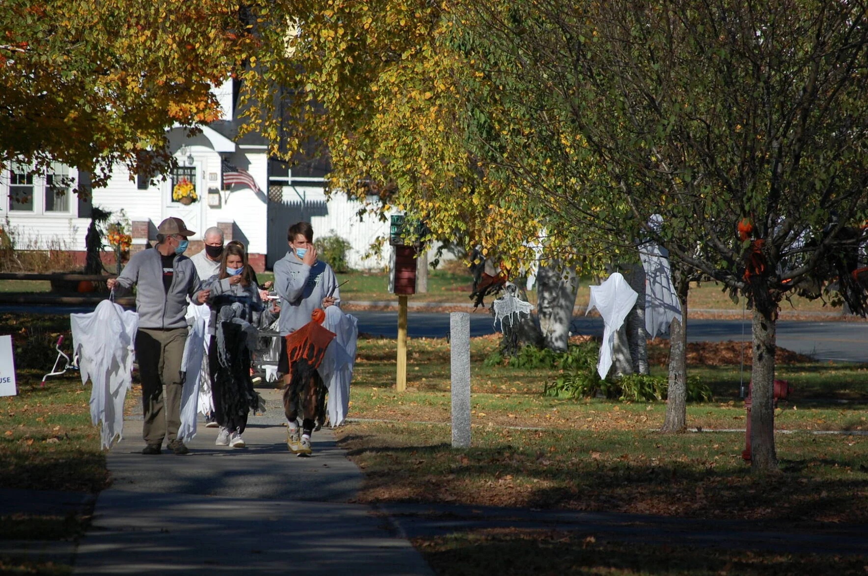 Halloween decorations and costumed people on a tree-lined street