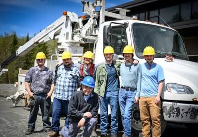 Graduating class of Vermont broadband technicians in hard hats standing in front of a bucket truck
